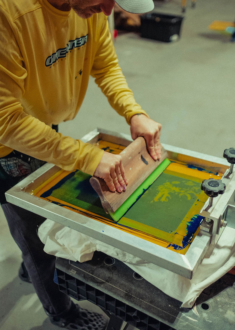 Artist and designer Jay Giroux screen printing a shirt in his studio.